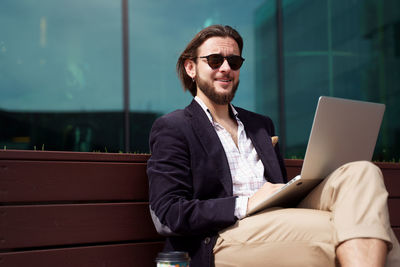 Portrait of smiling young businessman using laptop
