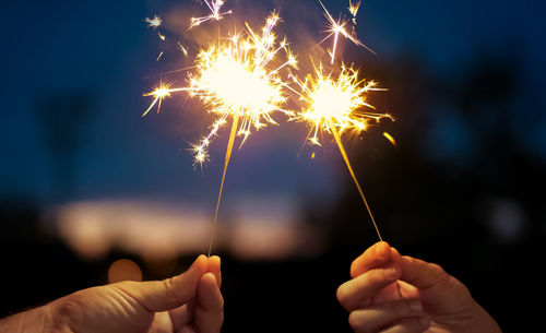 Hand holding firework display at night