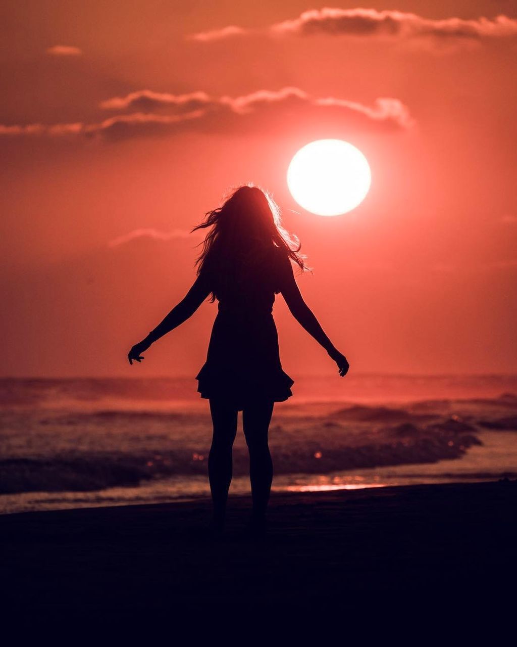 SILHOUETTE WOMAN STANDING ON BEACH AGAINST SUNSET SKY