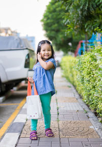 Portrait of smiling girl standing on footpath