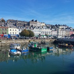 Boats moored at harbor against buildings in city