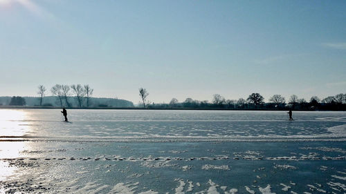 Man walking on frozen landscape against sky