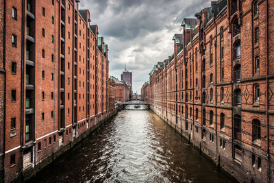 Canal amidst buildings in city against sky