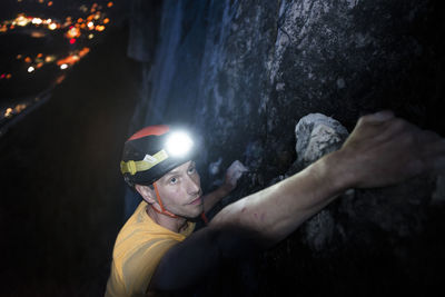 Top view man rock climbing at night above the sea and highway