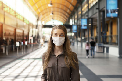 Portrait of woman wearing mask standing at railroad station