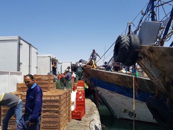 People working on boat against clear sky