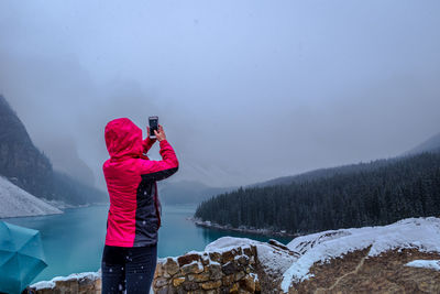 Rear view of woman photographing during winter