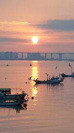 Boat moored in sea against sky during sunset