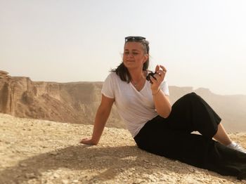 Full length of woman sitting against clear sky