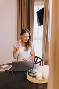 Portrait of woman sitting behind her laptop with hand in hair 