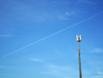 Low angle view of communications tower against blue sky