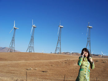 Woman standing on field against clear blue sky