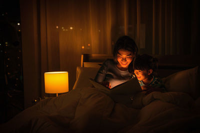 Young woman using mobile phone while relaxing on bed at home