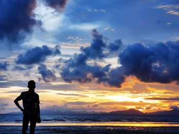 Silhouette man standing on beach against sky during sunset