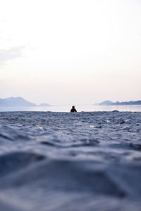 Man on beach against sky during sunset