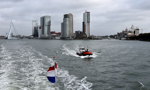 Nautical vessel on sea by buildings against sky