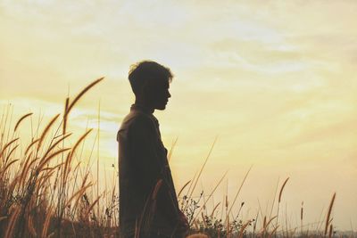 Side view of man standing on field against sky