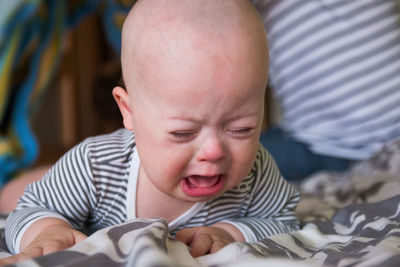 Close-up of baby boy crying while lying on bed at home