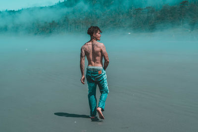 Full length of shirtless man standing in sea