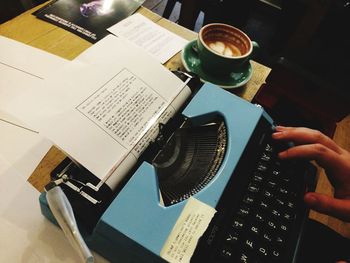 High angle view of hand holding coffee cup on table