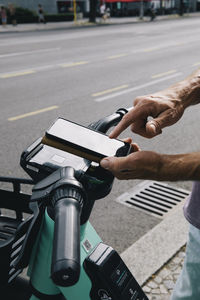 Close-up of hand unlocking electric push scooter using smart phone