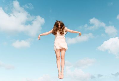 Rear view of woman with arms raised against sky