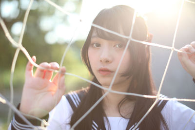 Portrait of young woman standing by sports net