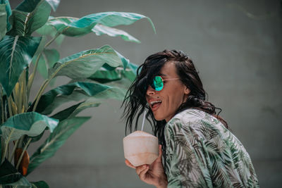 Portrait of smiling young woman holding leaf outdoors