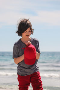 Cute boy with cap standing at beach