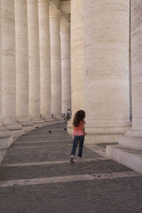 Full length rear view of woman walking in historical building