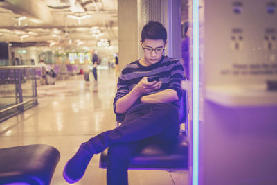 Man using mobile phone while sitting at airport