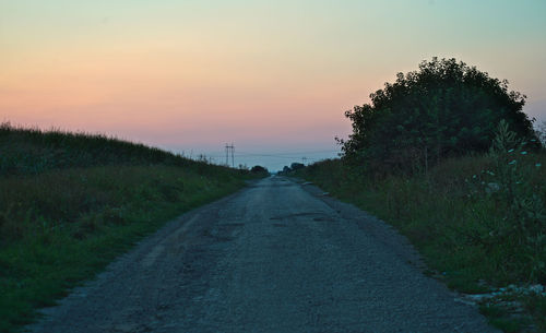 Road amidst trees against sky during sunset