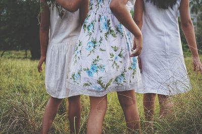 Midsection of friends standing on grassy field