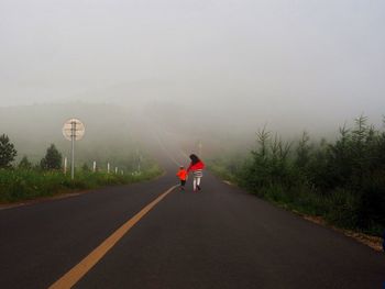 Rear view of children running on road