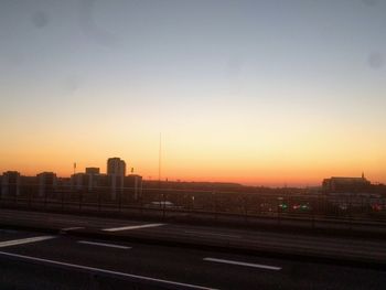 City street by buildings against sky during sunset