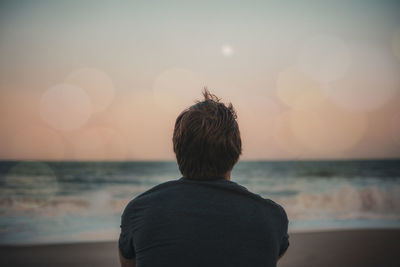 Rear view of man looking at sea against sky