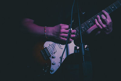 Midsection of man playing guitar