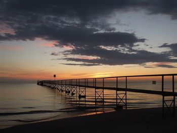 Silhouette pier over sea against sky during sunset