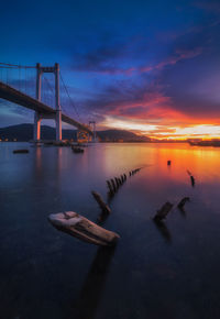 Bridge over sea against sky during sunset