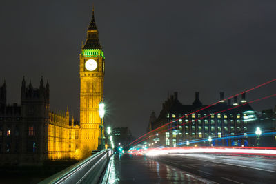 Light trails on bridge by big ben at night