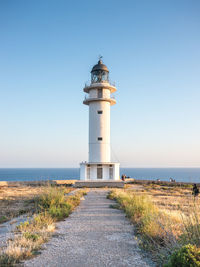 Lighthouse by sea against clear sky