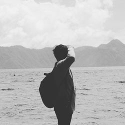 Side view of man looking at sea against mountains and sky