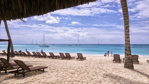 Deck chairs on beach against sky