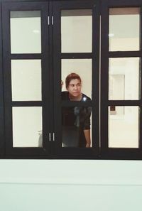 Portrait of man looking through window in building