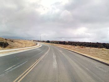 Empty road amidst land against sky