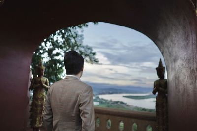 Rear view of man looking through archway