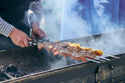 Midsection of man preparing food on barbecue grill