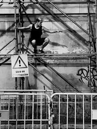 Full length of shirtless man standing on railing