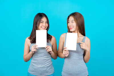 Portrait of a smiling young woman standing against blue background