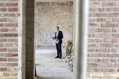 Male architect with digital tablet standing at construction site